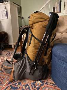 Orange backpack from the side with trekking poles