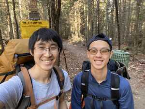 Two Asian men in the woods with backpacks on