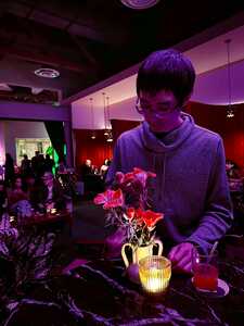Asian man in purple light at a bar with candle and flowers