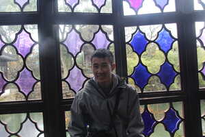 Asian man in front of stained glass window